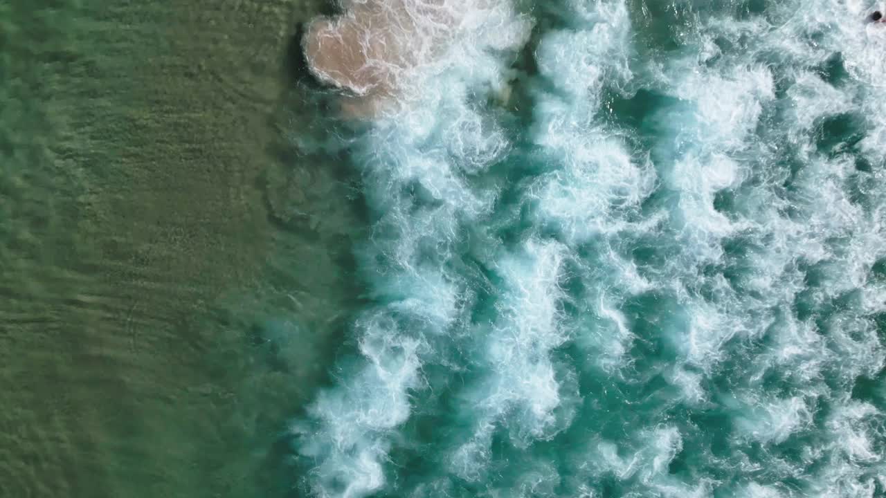4K鸟瞰图在悉尼夏季周末的中午，标志性的邦迪海滩的水边和海浪的实时镜头俯视图视频下载