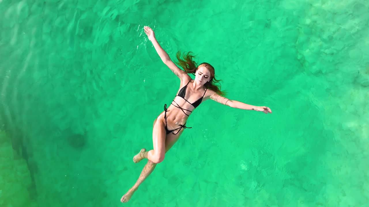 在埃及的锡瓦绿洲，一名年轻女子仰面漂浮在绿松石色的盐水池中。视频下载