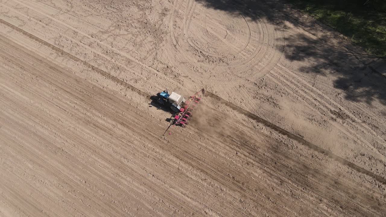鸟瞰图，一个农民在一辆旧的蓝色拖拉机上播种玉米视频素材
