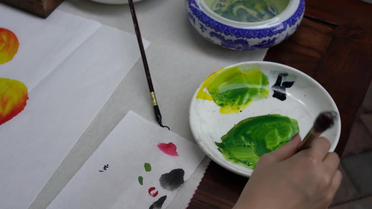 一位画家正在创作中国画，并用调色板给它们上色视频下载