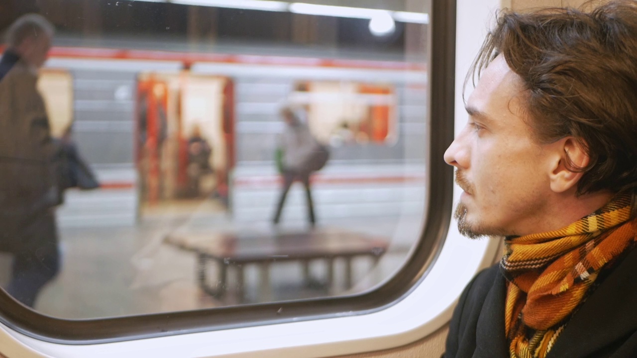 孤独沉思的男人在地铁里望向窗外，一列地铁，生命的流动，时间的流逝，慢动作。人们做自己的事。视频下载