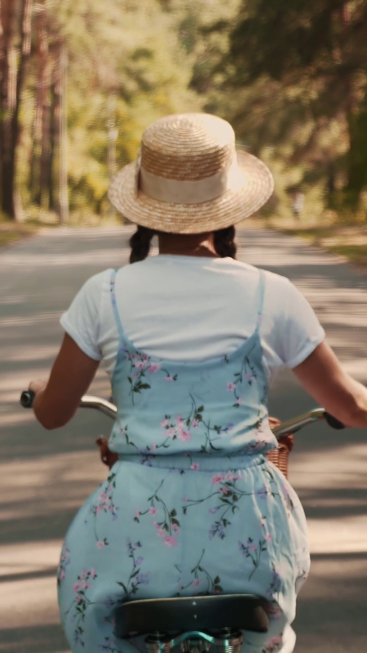 浪漫的女人在公园里骑着复古的老式自行车。垂直视频视频下载