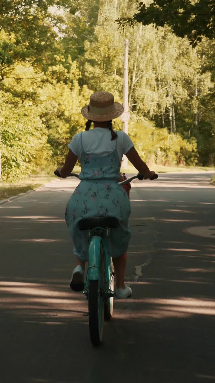 背部跟随拍摄女子骑复古自行车在公园在夏天。垂直视频视频下载