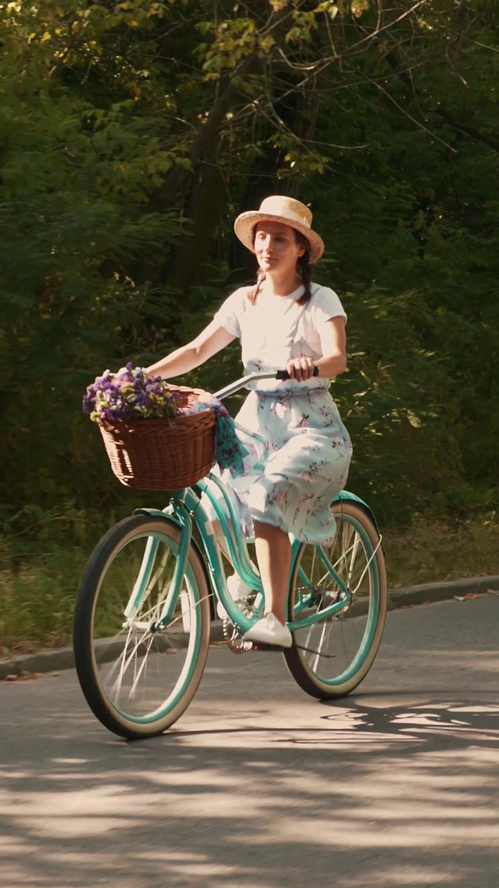 夏天的绿色公园里，一名女子骑着复古的自行车。垂直视频视频下载
