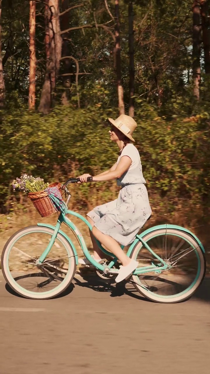 戴草帽的黑发女子在公园里骑着复古自行车。垂直视频视频下载