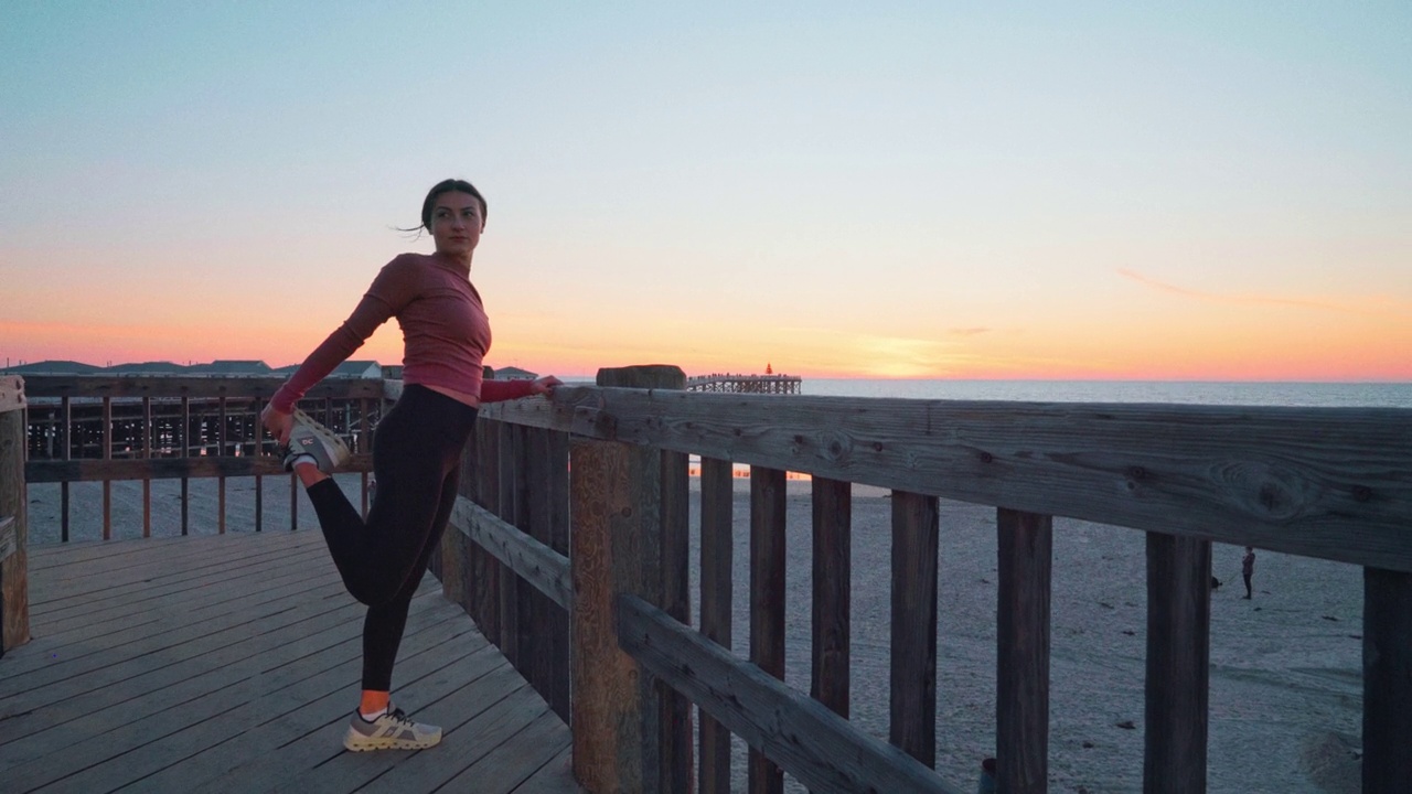 在加州圣地亚哥，欢快的年轻慢跑女性在看日落时伸展身体跑步视频下载