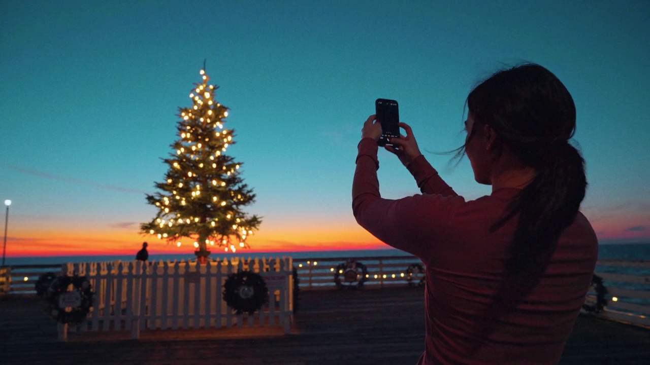 在圣地亚哥的水晶码头上，年轻的慢跑女子休息时拍摄了一棵发光的装饰圣诞树视频下载
