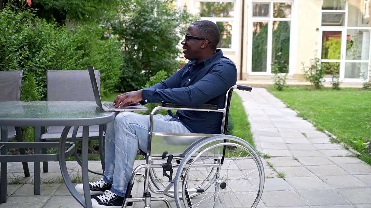 一个残疾人在花园里用笔记本电脑工作视频素材