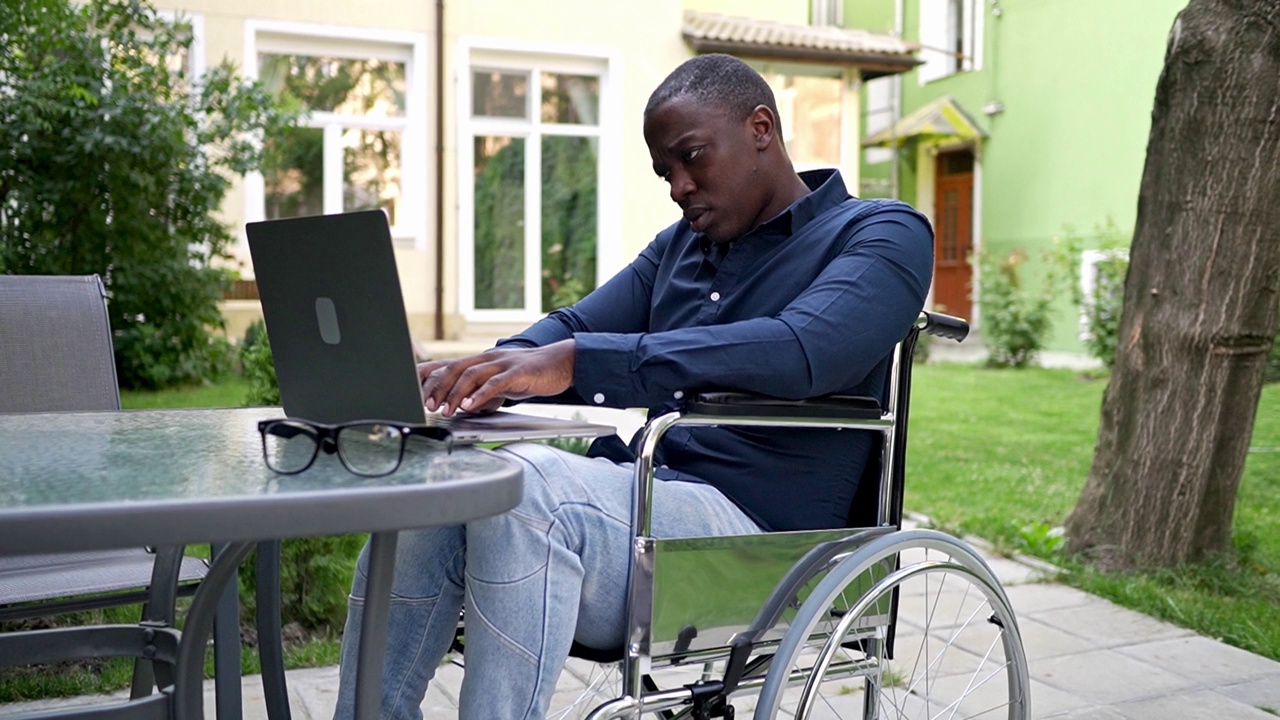 一个孤独的残疾人在花园里用笔记本电脑工作视频素材