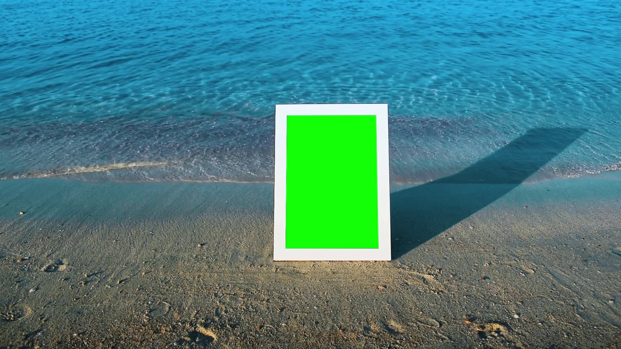 白色的相框立在海边的沙滩上。视频下载
