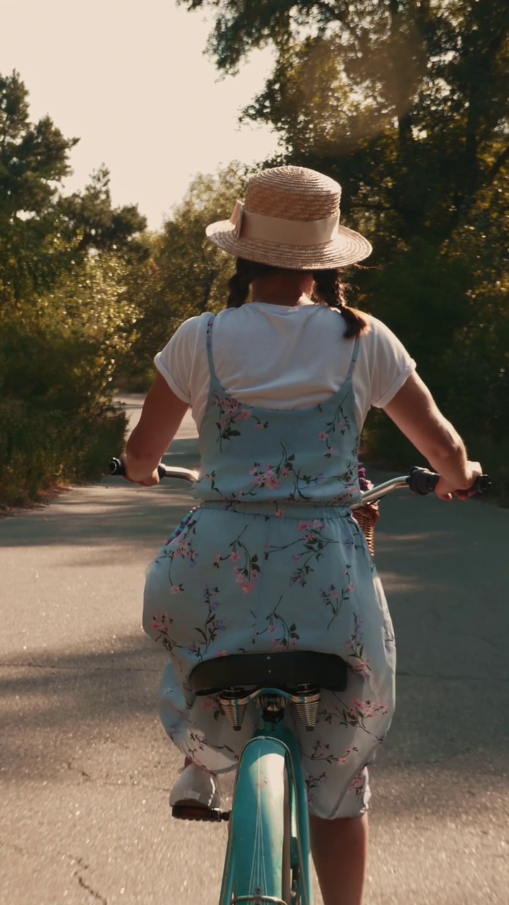 后面跟着拍的女性骑着复古自行车在公园。垂直视频视频下载