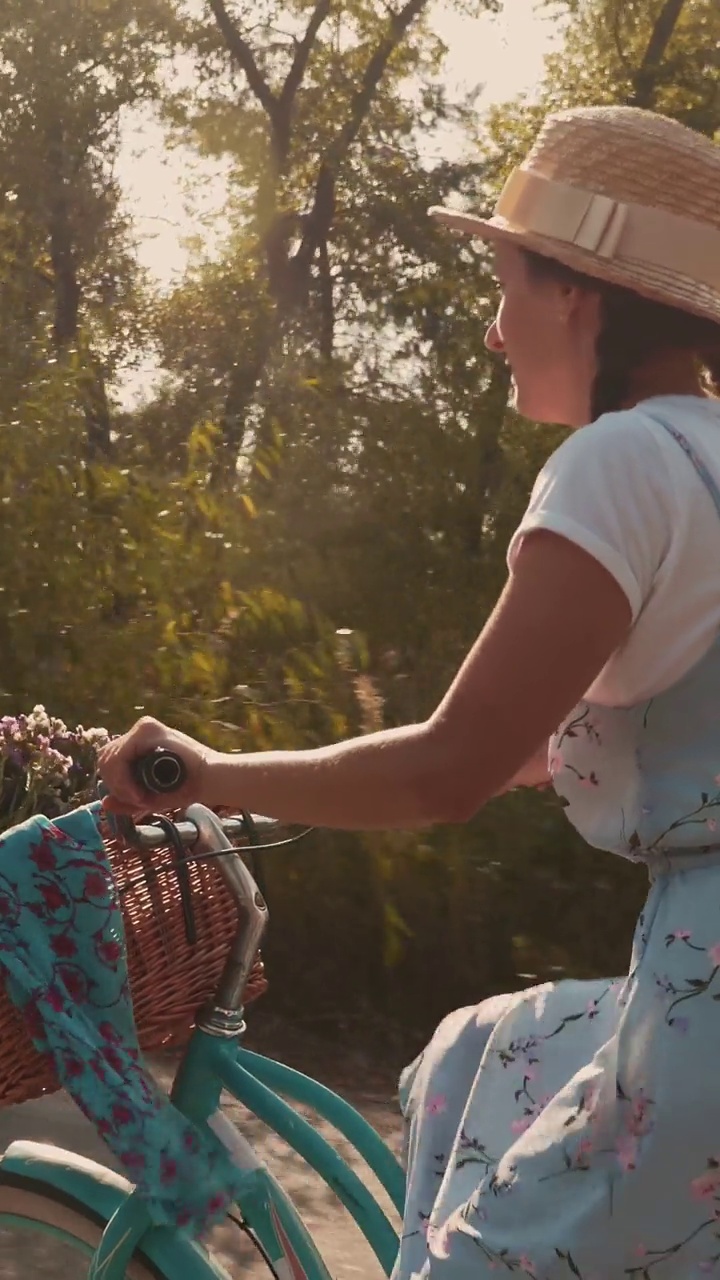 在绿色的公园里，一个女人骑着复古的自行车，带着篮子和鲜花。垂直视频视频下载