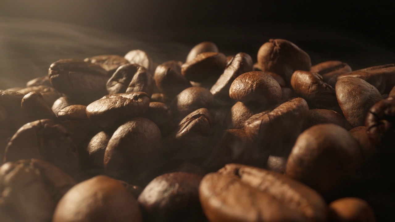 在黑背景下用烟熏咖啡豆。烟来自新鲜的咖啡籽。咖啡豆在烘焙过程中的滑块镜头。UHD 4 k视频素材