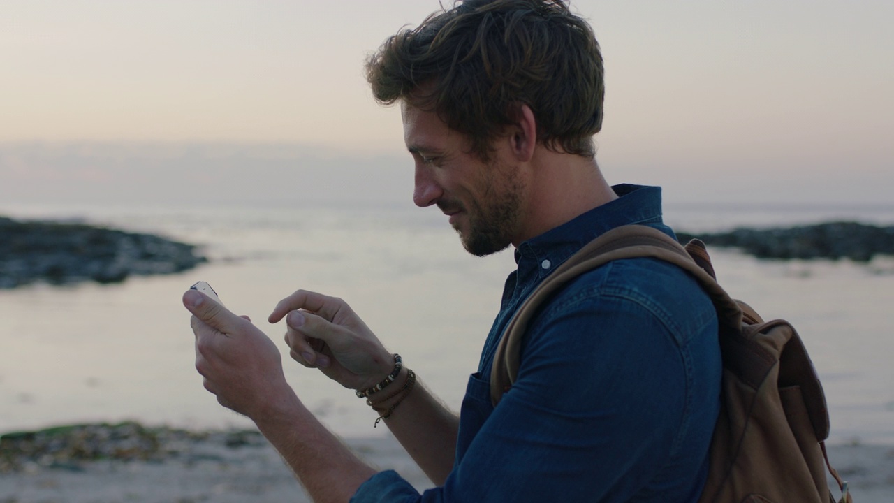白人男子在海滩上用手机拍摄美丽的海边海洋的肖像视频素材