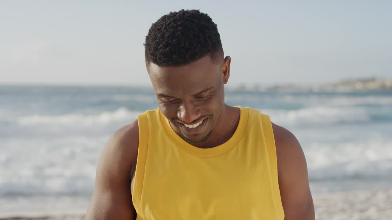 年轻健康的非洲裔美国人在海滩度假时穿着黄色背心，用智能手机拍照，微笑着享受移动技术视频素材