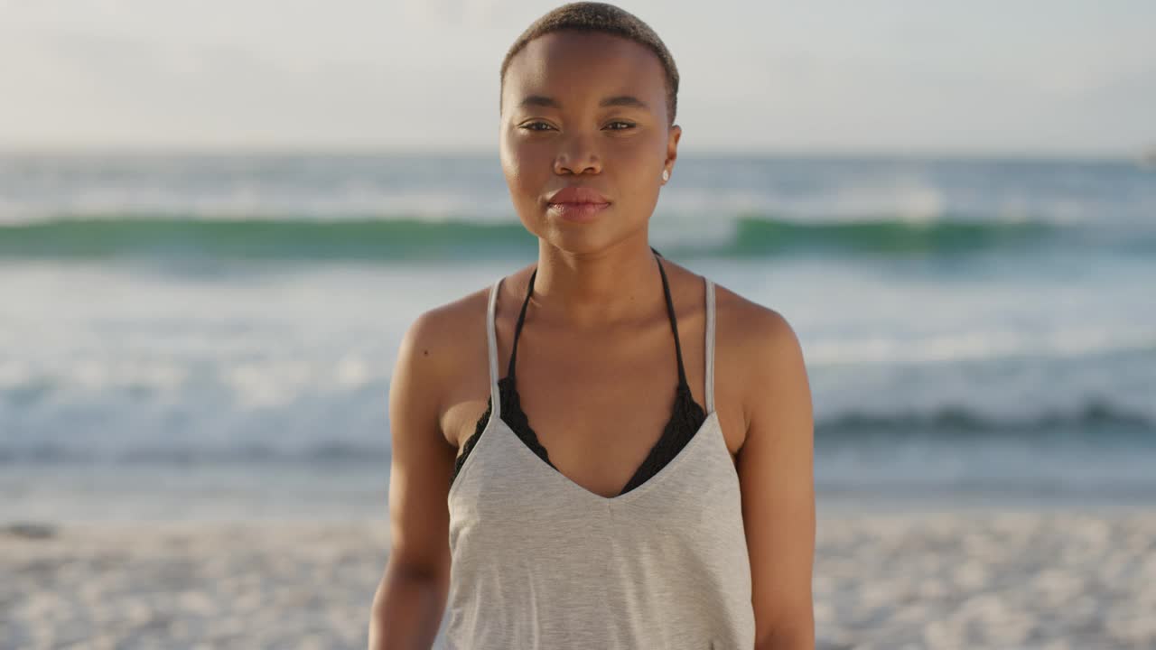独立的非洲裔美国妇女在夏天的海滩上，看着相机严肃沉思视频下载