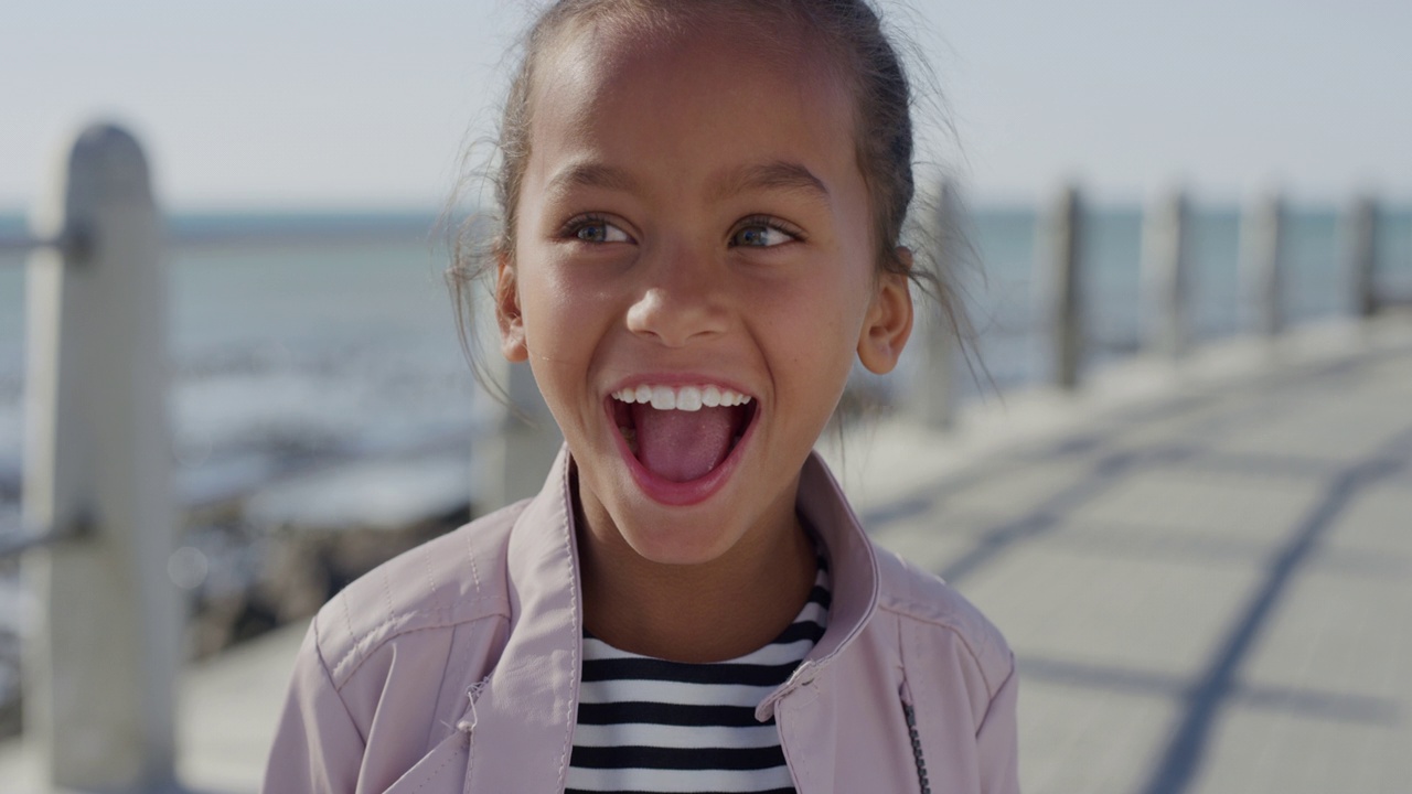 肖像小混血女孩笑兴奋享受美丽的阳光明媚的一天在海边的海滩视频下载