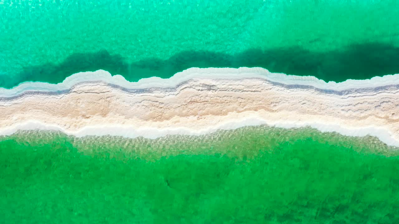一名年轻女子在锡瓦绿洲的蓝色和绿色盐池之间行走的无人机视频，从上面形成了迷人的对比。视频下载