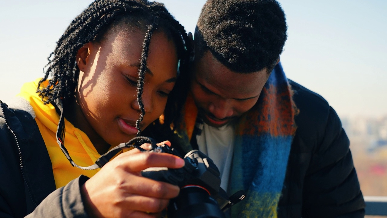 年轻漂亮的非裔美国女游客在男性朋友面前摆姿势拍照视频素材