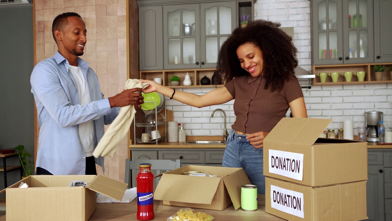 一名妇女和她多元化的男友在家里把食物装进纸板捐款箱视频素材