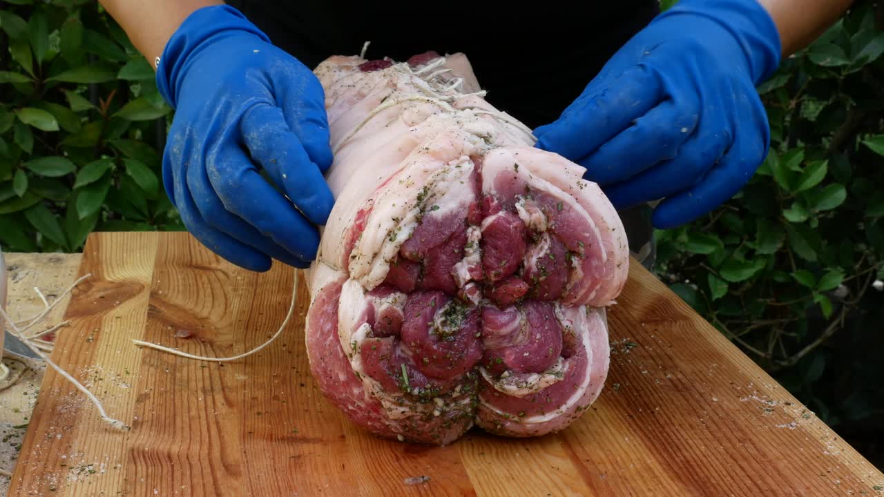 屠夫把肉卷起来准备烤猪肉视频下载