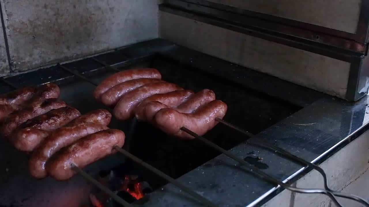 在巴西烤肉上，串在烤肉串上的猪肉香肠被翻过来煎另一面。视频下载
