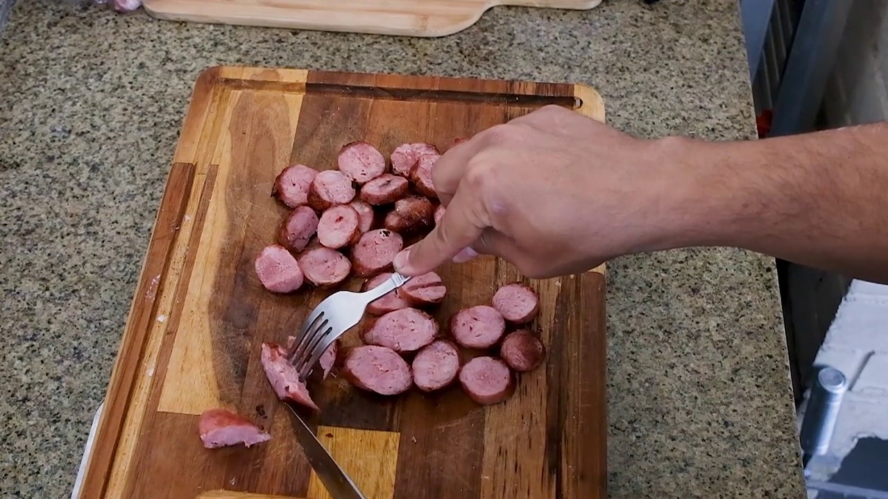 一名男子在木板上切猪肉香肠。视频素材