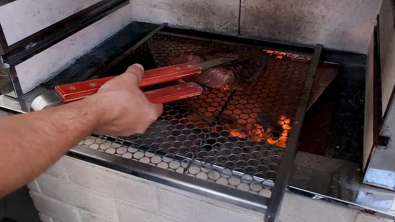 在巴西烤肉会上，一名男子用夹子夹牛腰肉。视频下载