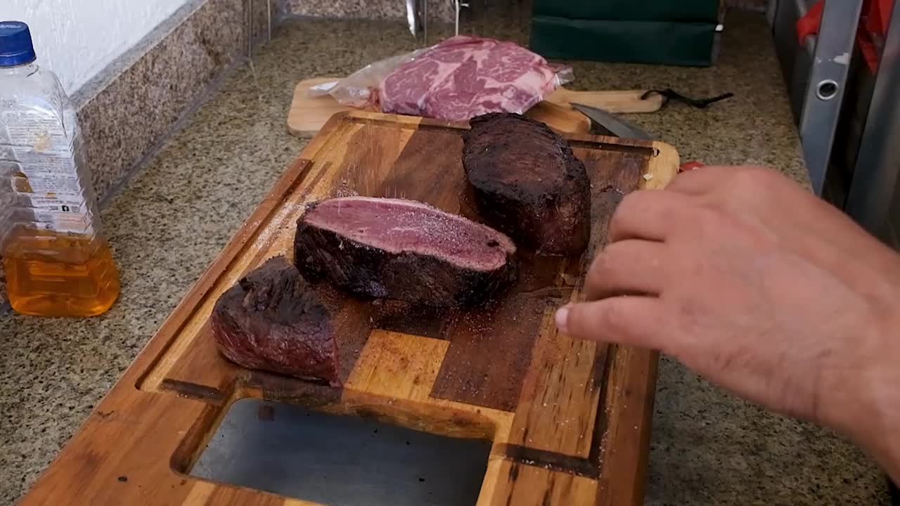 一名男子在把牛腰肉放回火上烤之前，在上面撒盐。视频下载