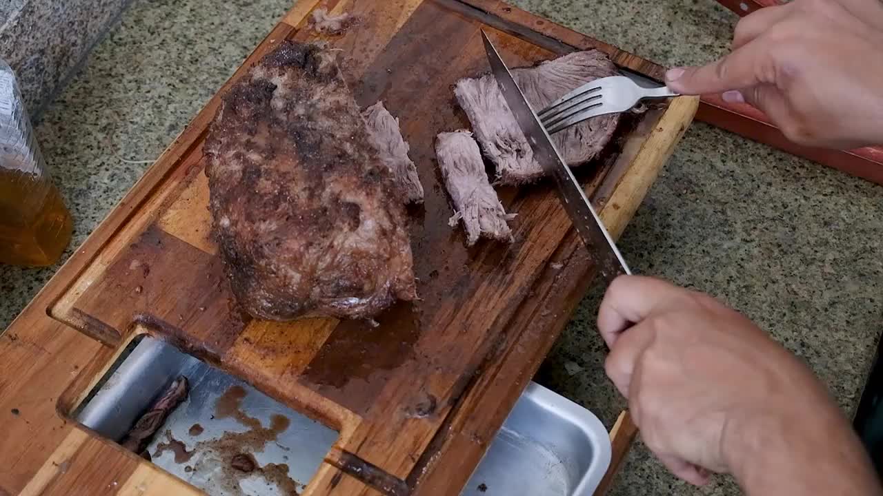 一名男子将一块驼背牛排切成小块供人食用。视频素材