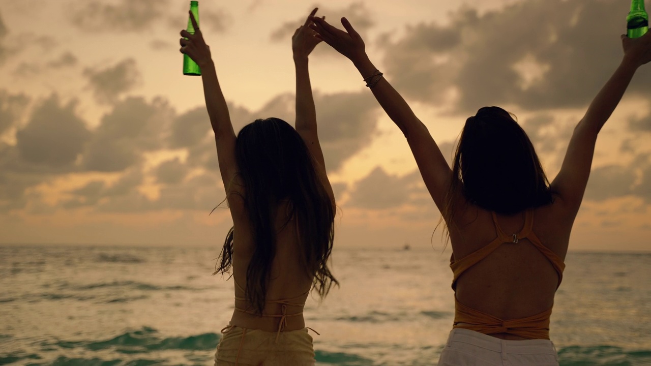 两个美丽的亚洲女人在日落的海滩上跳舞，度假，自由的概念，旅游，冒险，无忧无虑视频购买