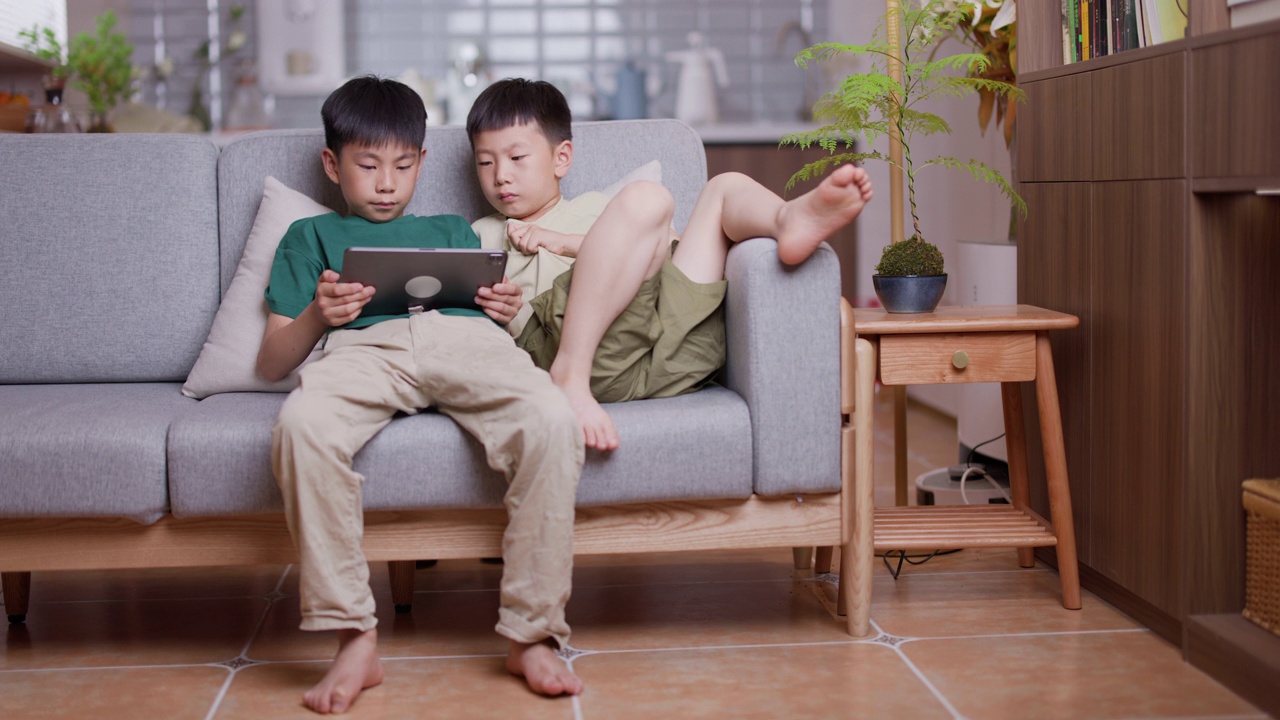 两个男孩在家里玩数码平板电脑视频素材