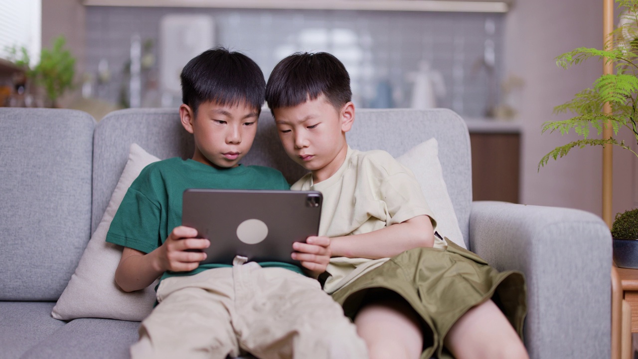 两个亚洲男孩在家里使用数字平板电脑进行在线学习视频素材