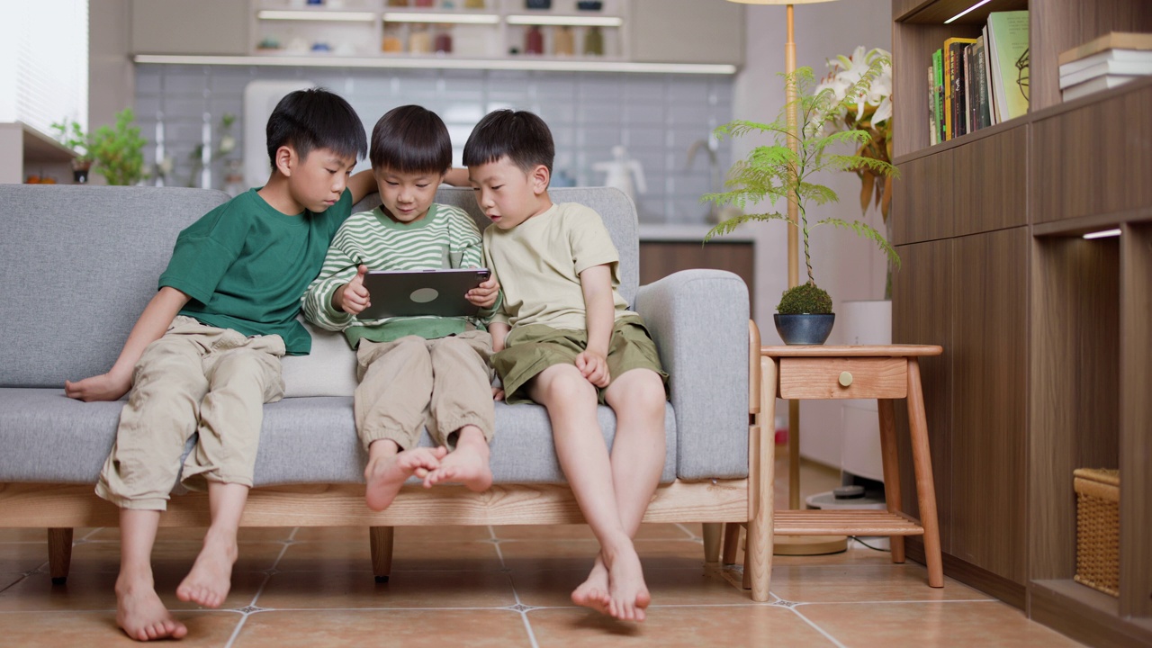 三个男孩在家里玩电子平板电脑游戏视频素材