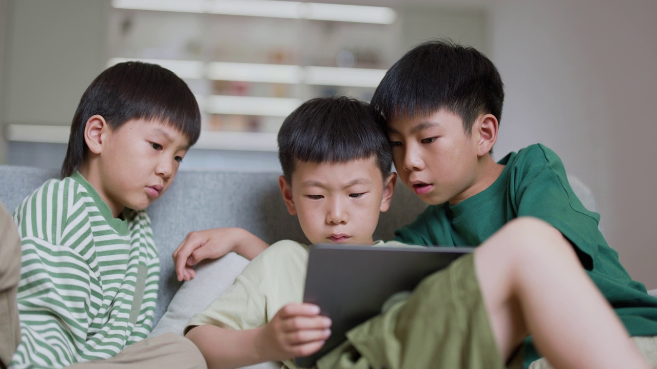 三个男孩在家里使用数字平板电脑进行在线学习视频素材