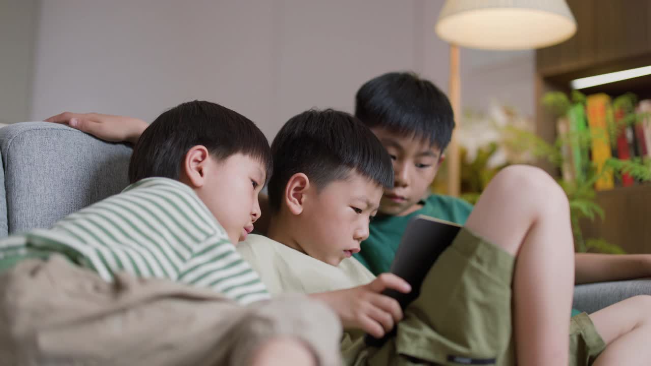 三个亚洲男孩在家里用平板电脑看视频视频素材
