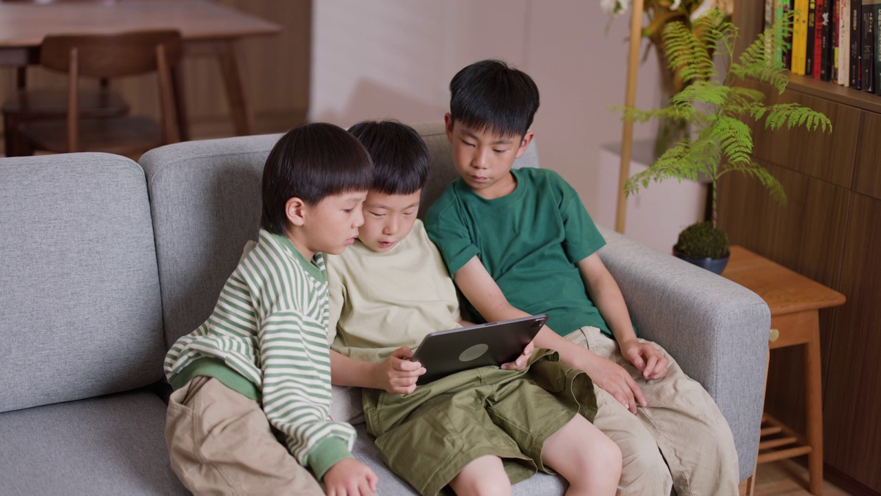三个男孩在家里用平板电脑看视频视频素材
