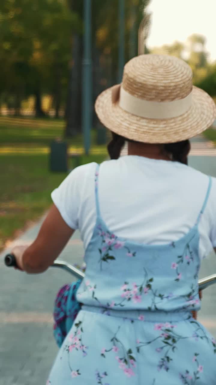 在公园里骑复古复古自行车的女性的背影跟随镜头。垂直视频视频下载