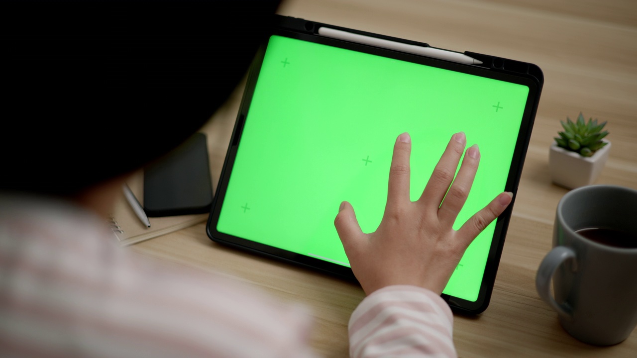 年轻的女性正在用空白的绿屏模拟平板电脑工作视频下载