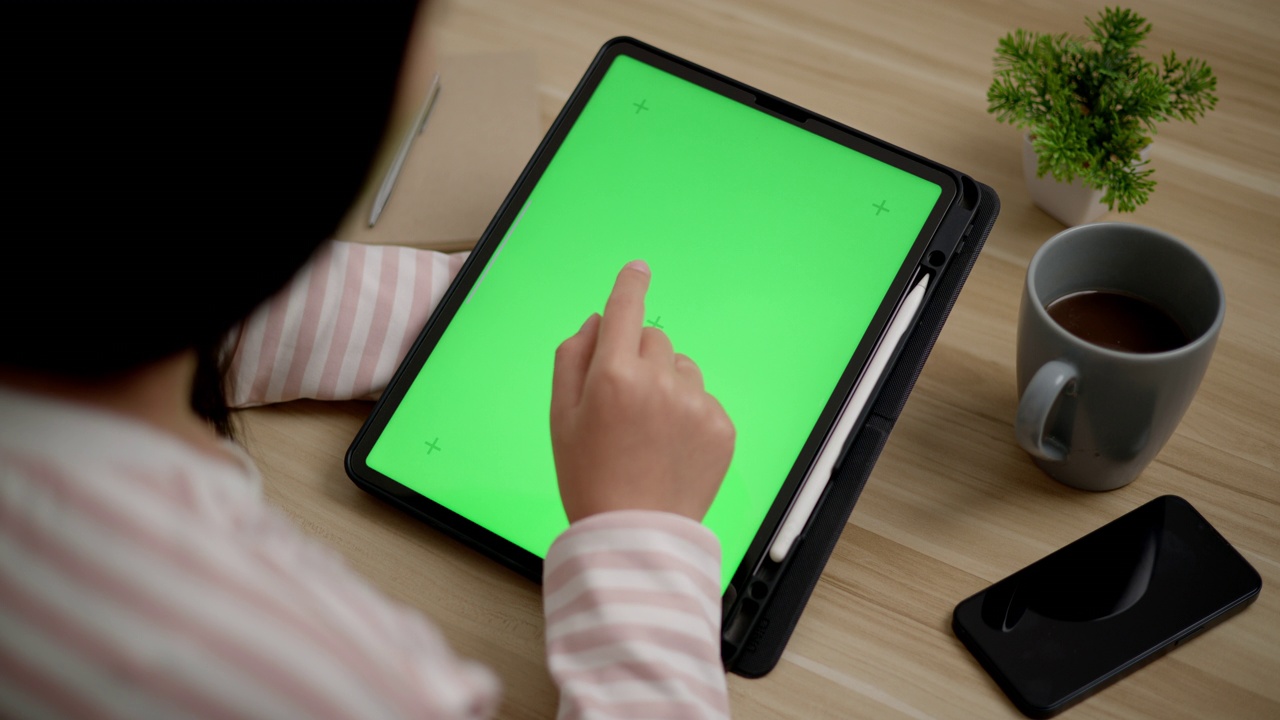 年轻的女性正在用空白的绿屏模拟平板电脑工作视频素材