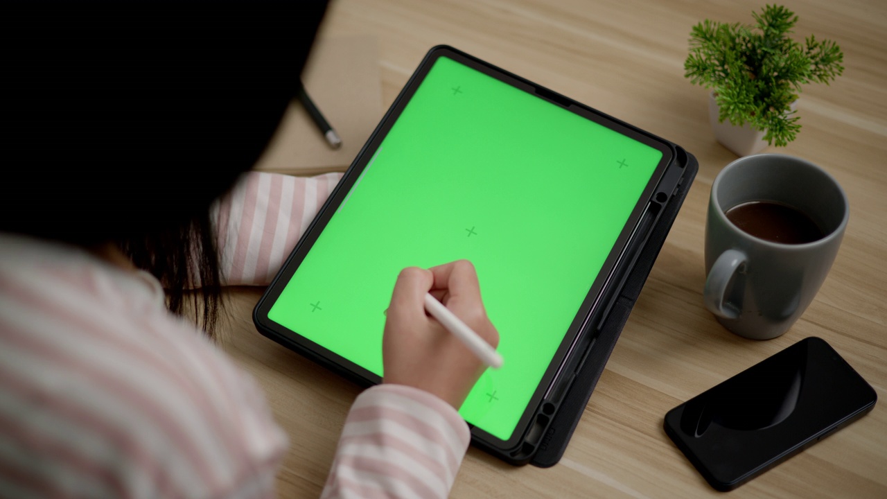 年轻的女性正在用空白的绿屏模拟平板电脑工作视频下载