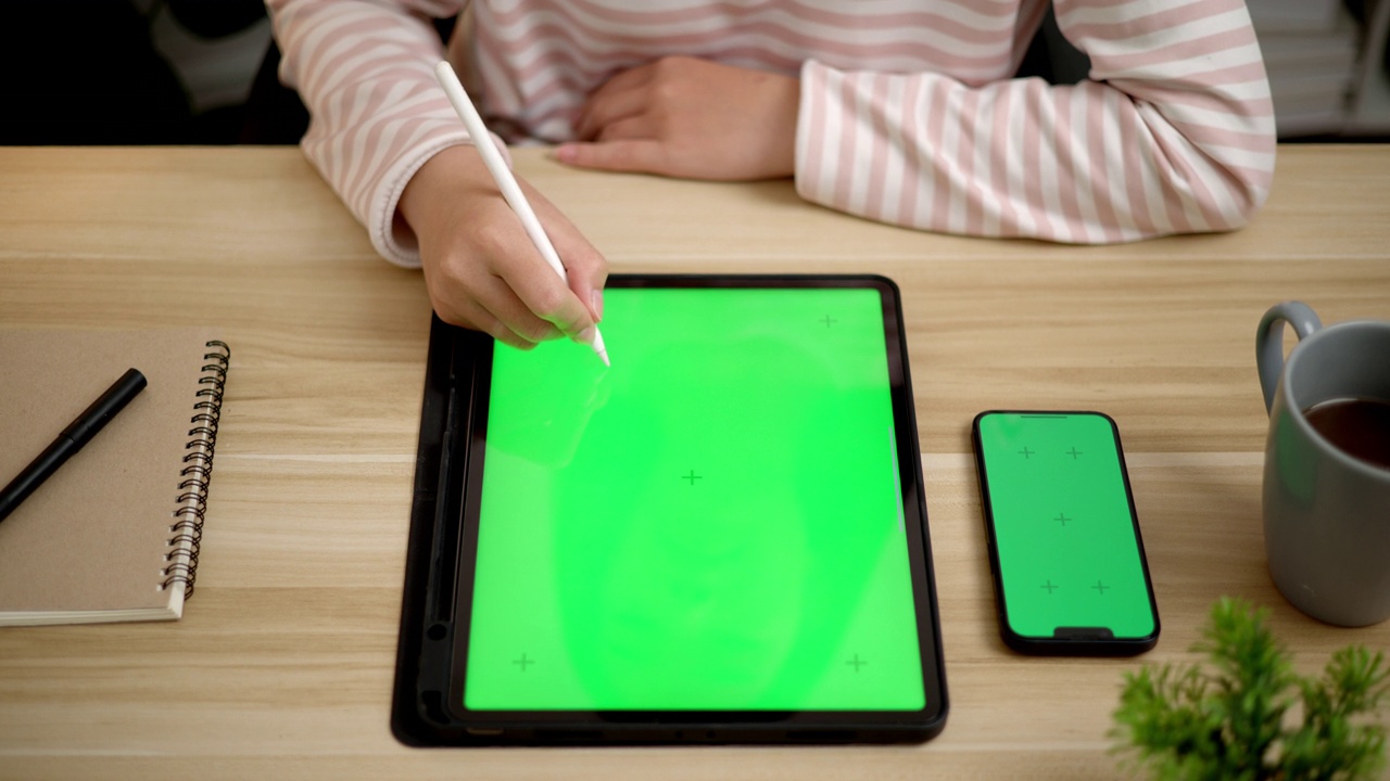 年轻的女性正在用空白的绿屏模拟平板电脑工作视频素材
