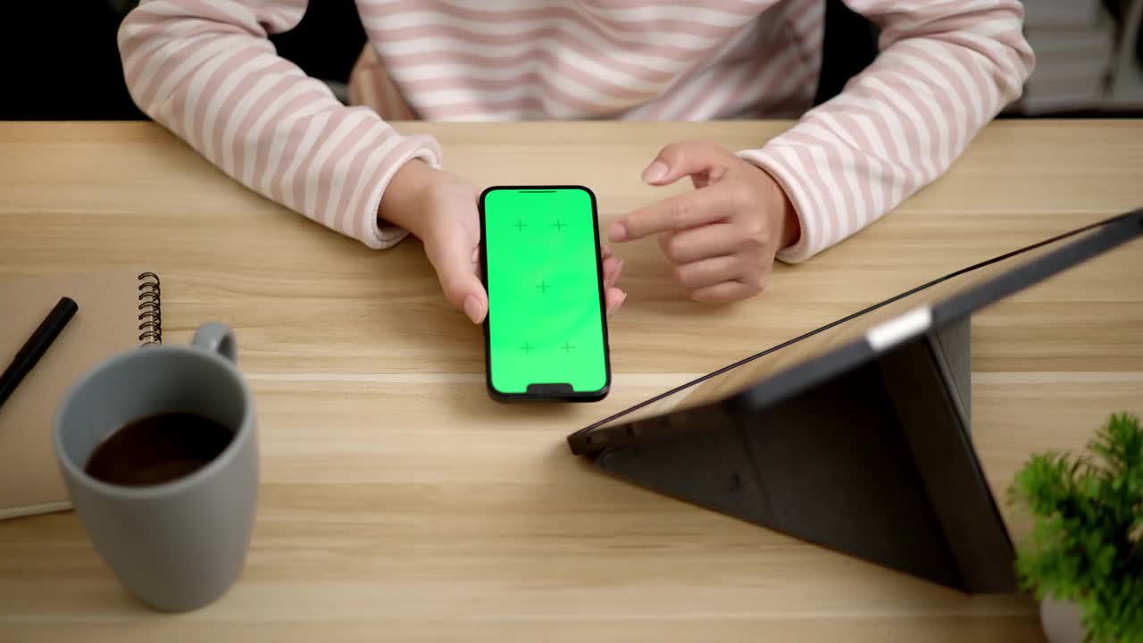 年轻女性在智能手机上敲打着空白的模拟绿色屏幕，上面有标记视频下载