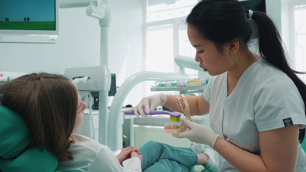 可爱的亚洲女牙医向病人展示如何正确刷牙视频下载