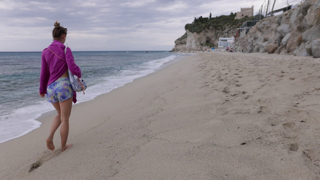 十几岁的女孩穿着沙滩巾走在沙滩上视频下载