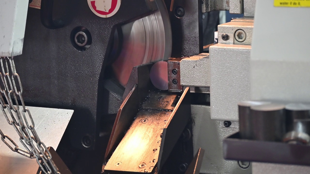 近距离拍摄带锯切割机切割金属轴类零件的操作场景。视频素材