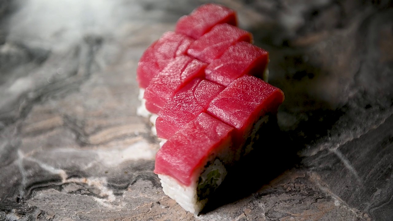 制作寿司卷的过程。寿司师傅用刀将寿司卷切成小块。视频下载