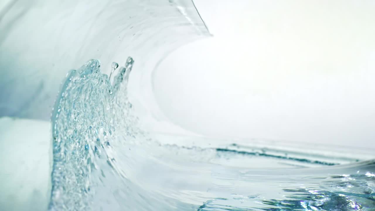 近距离和缓慢的运动，巨大的水晶般清晰的波浪在白色的背景下有力地旋转。视频下载