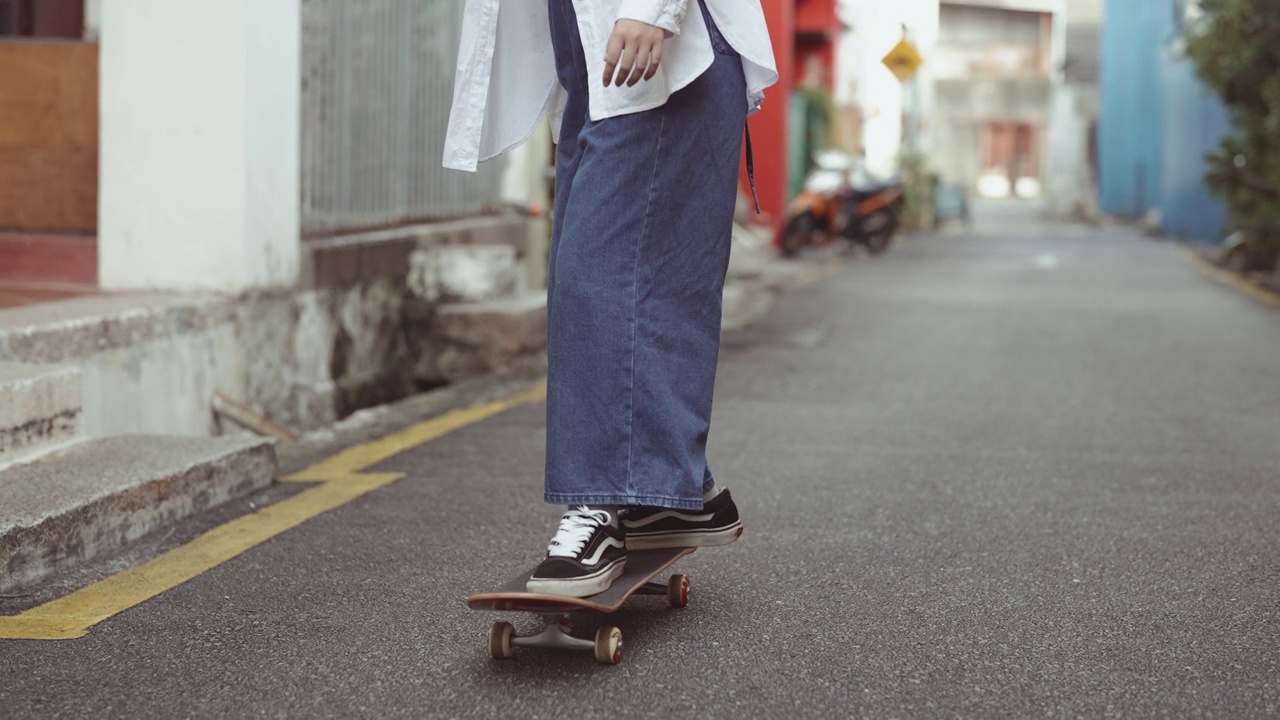 亚洲华人年轻女子在槟城老城区的小巷里玩滑板视频下载
