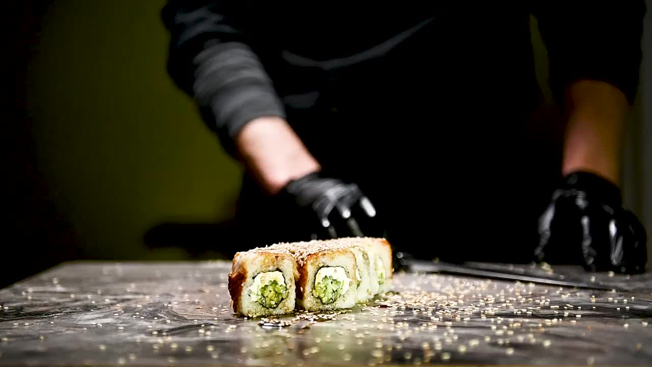 制作寿司卷的过程。寿司师傅用刀将寿司卷切成小块。视频下载